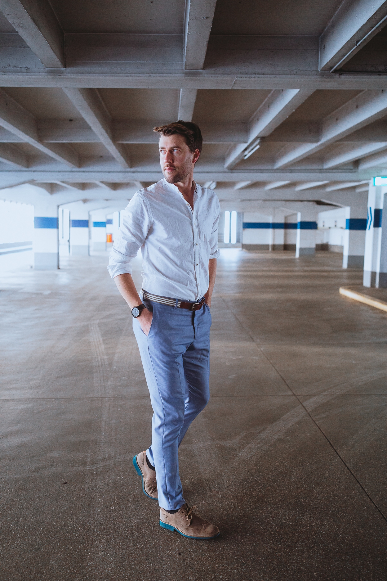 Das etwa 1,80 Meter große, brünette männliche Model Axel posiert in einem Parkhaus in der Abendsonne bei einem Shooting mit dem Münchner Fotograf Daniel Schubert.