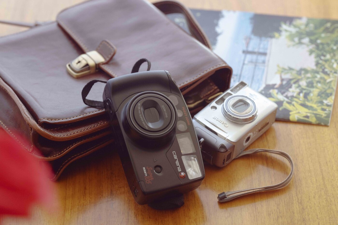 Point and shoot cameras on a table next to a catalog.